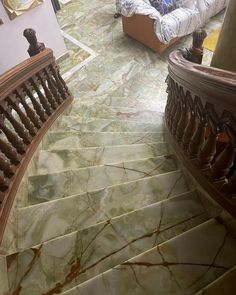 a marble staircase with wooden handrails in a living room next to a couch