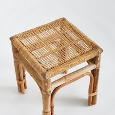 a wicker stool made out of wood and rattan with one foot on it