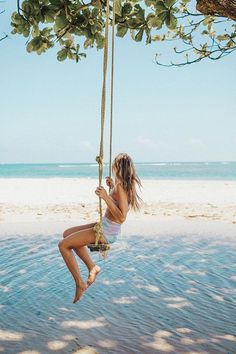 a girl swinging on a rope at the beach