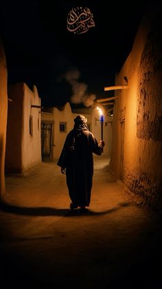 a man holding a lit candle in his hand while walking down an alley way at night