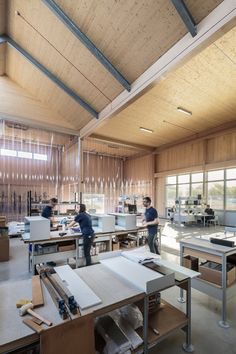 two men are working in a large wood - paneled room with lots of tables