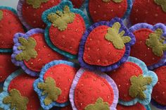 a pile of red and blue felt strawberries with gold sequins on them