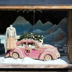 a window display with a pink car decorated for christmas