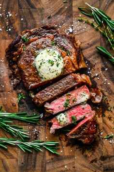 sliced steak with butter and chives on top, sitting on a wooden cutting board