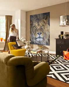 a woman standing in a living room with a lion painting on the wall