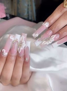 a woman's hands with pink and white flowers on them, holding onto her nails