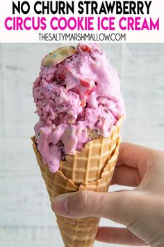 a hand holding an ice cream cone with pink icing