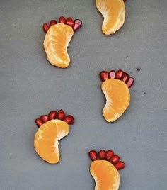 four orange slices with red candies in the shape of feet