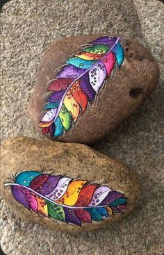 two rocks with colorful feathers painted on them