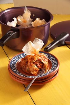 a plate with some food on it next to a pot filled with rice and other items