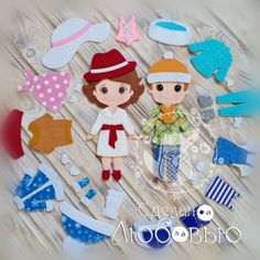 two dolls standing next to each other on a wooden table with paper cut outs around them