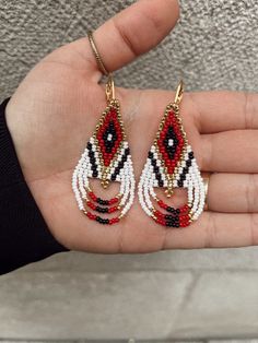 a hand holding two pairs of beaded earrings on it's left and right palm