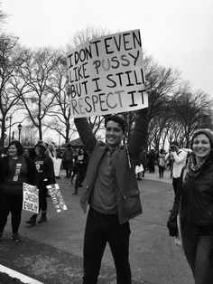 a man holding up a sign while standing next to other people in the street with signs