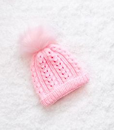 a pink knitted hat with a pom - pom sitting on top of it