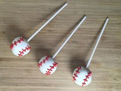 three cake pops with red stitches on them sitting on a wooden table next to each other