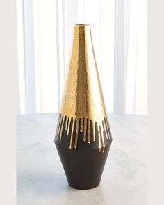 a black and gold vase sitting on top of a white table next to a window