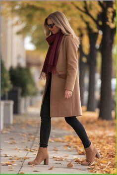 This look features a timeless camel coat paired with black skinny jeans and tan ankle boots, creating a refined yet casual style perfect for fall.  The addition of a burgundy scarf adds a pop of colour, making the outfit both stylish and functional.  This ensemble works well for city strolls or casual meetings, providing warmth without sacrificing elegance. Fall Outfits Women With Scarf, Burgundy Scarf Outfit Winter, Camel Coats For Women, Winter Meeting Outfit, Fall Outfit With Scarf, Casual Elegant Outfits Winter, Caramel Boots Outfit, Tan Boots Outfit Ankle Winter, Coat Scarf Outfit