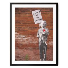 an old man holding a sign with the words love is the answer in front of a brick wall