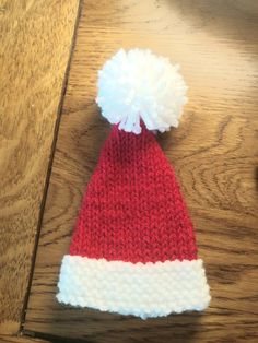 a red and white knitted hat sitting on top of a wooden table