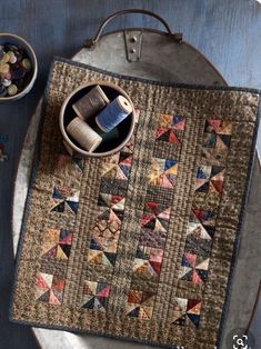 a quilted placemat with scissors and thread spools in it on a plate