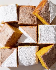 several pieces of cake sitting next to each other on a white table top with powdered sugar