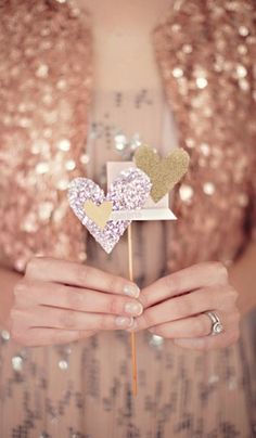 a close up of a person holding a cake topper in their hands with hearts on it