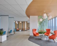 an office with large windows and colorful chairs in front of the window are two planters on either side of the glass wall