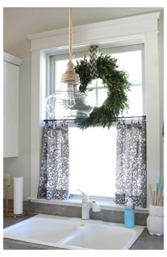 a kitchen sink with a wreath hanging from the window