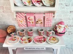 a table topped with lots of cups and saucers next to a shelf filled with plates