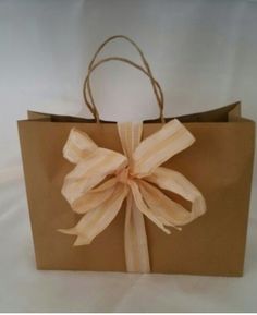 a brown paper bag with a large bow on it's front and side handles