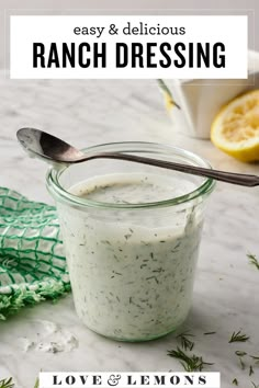 a glass jar filled with ranch dressing on top of a white tablecloth next to a lemon slice