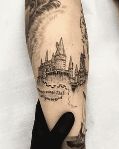 a person with a black and white tattoo on their arm that has an image of hogwart's castle