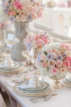 the table is set with pink and white flowers in vases, silverware, and plates