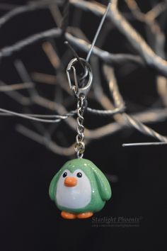 a green and white penguin keychain hanging from a tree