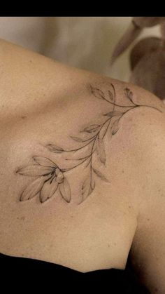 the back of a woman's shoulder with flowers tattoo on her left arm and chest