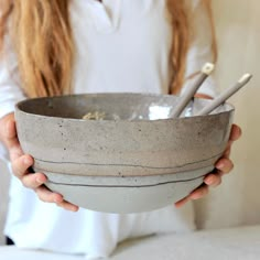 a person holding a bowl with two spoons in it