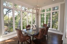 a dinning room table and chairs in front of large windows