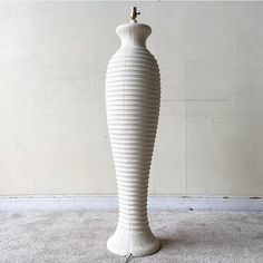 a tall white vase sitting on top of a carpet