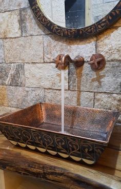 a sink that has water running from it in front of a mirror on the wall