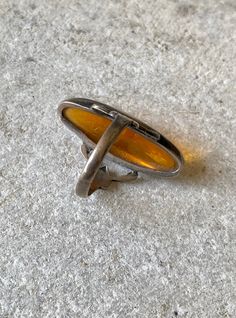 an old silver ring with yellow glass in the middle on concrete floored area next to sidewalk