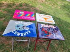 four different colored tables sitting on top of a grass covered field next to each other