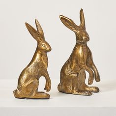 two golden metal rabbits sitting next to each other