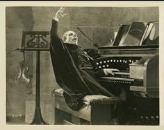 an old black and white photo of a man sitting in front of a pipe organ