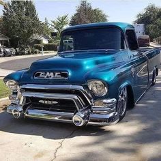 an old blue truck is parked on the street