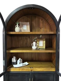 an arched wooden shelf with two vases on top and one potted plant in the middle