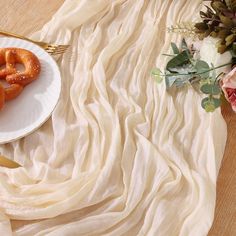 two pretzels are on a white plate next to a bouquet of flowers and a gold fork