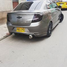 the back end of a silver car parked in front of a yellow car on a city street