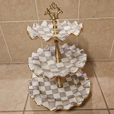 three tiered serving tray with checkerboard design on the bottom and gold accents