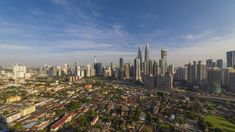 an aerial view of a large city with tall buildings and lots of green trees in the foreground