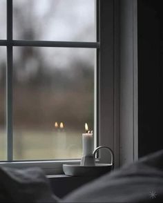 a lit candle sitting on top of a window sill